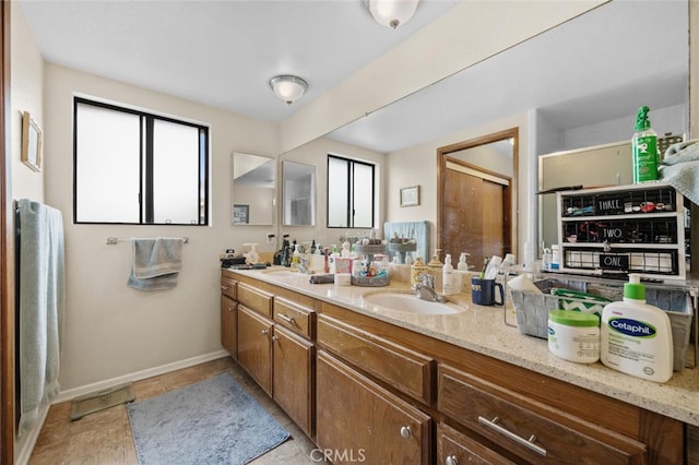 full bathroom with double vanity and baseboards