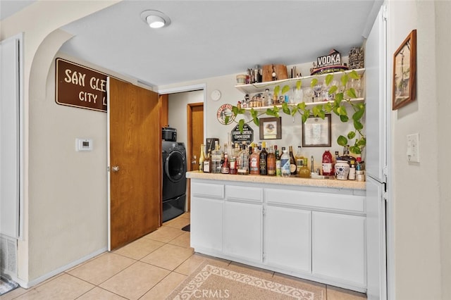 indoor dry bar featuring washer / clothes dryer and light tile patterned flooring