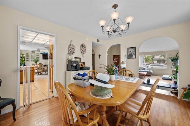 dining room featuring arched walkways, a chandelier, and light wood-type flooring