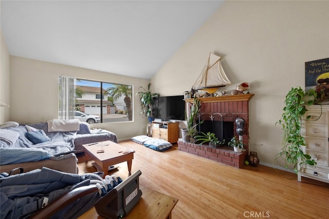living area featuring wood finished floors, a brick fireplace, and vaulted ceiling