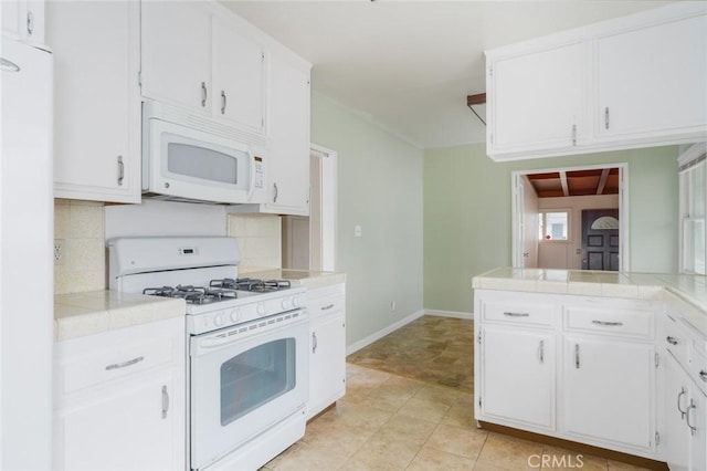 6016 Wilson Ave, South Gate, CA 90280 - kitchen featuring white appliances, tasteful backsplash, white cabinetry, and tile counters