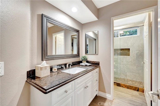 bathroom with a walk in shower, vanity, and baseboards
