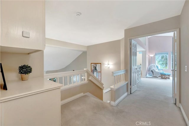 hall with light colored carpet, baseboards, lofted ceiling, and an upstairs landing