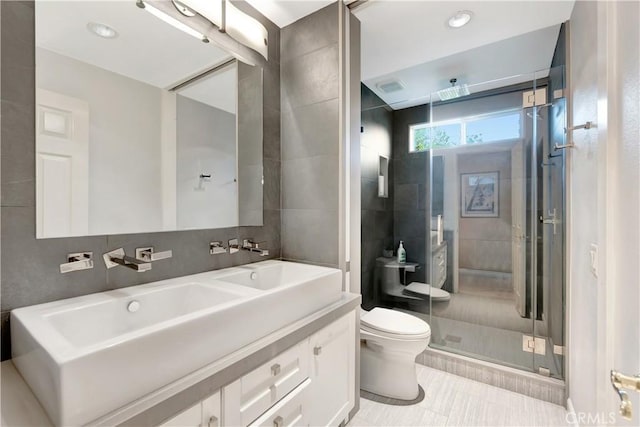 bathroom featuring a stall shower, toilet, tile walls, vanity, and tile patterned flooring