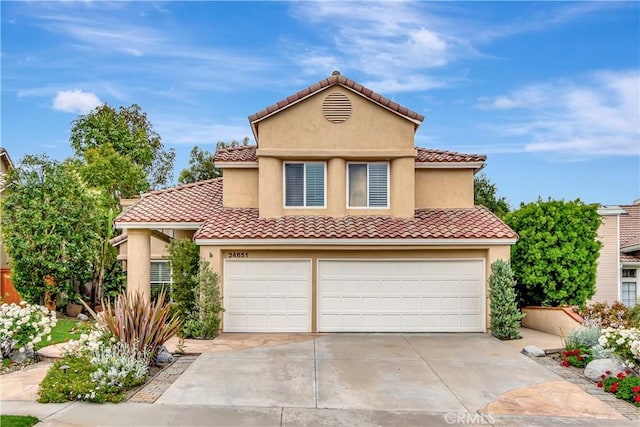 mediterranean / spanish house with driveway, stucco siding, and a tiled roof