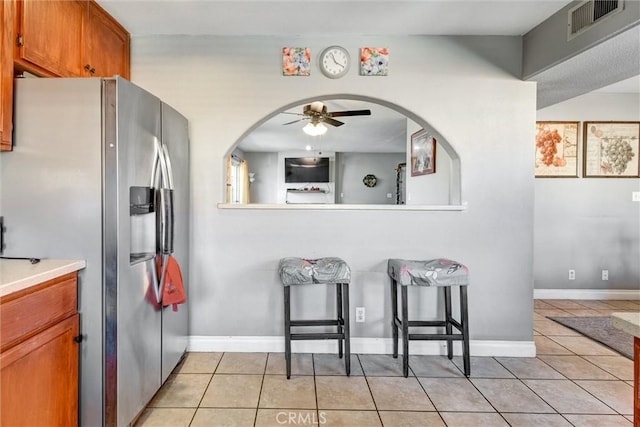 13580 Foothill Blvd Unit 1, Sylmar, CA 91342 - kitchen with stainless steel fridge with ice dispenser, light tile patterned flooring, ceiling fan, brown cabinets, and light countertops