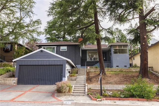 view of front of property with an attached garage, concrete driveway, stairway, and a chimney
