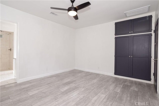 unfurnished bedroom with light wood-type flooring, baseboards, a ceiling fan, and connected bathroom