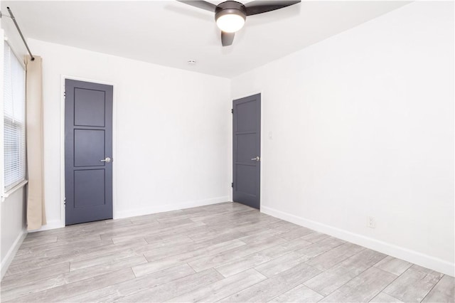 unfurnished room with ceiling fan, light wood finished floors, and baseboards