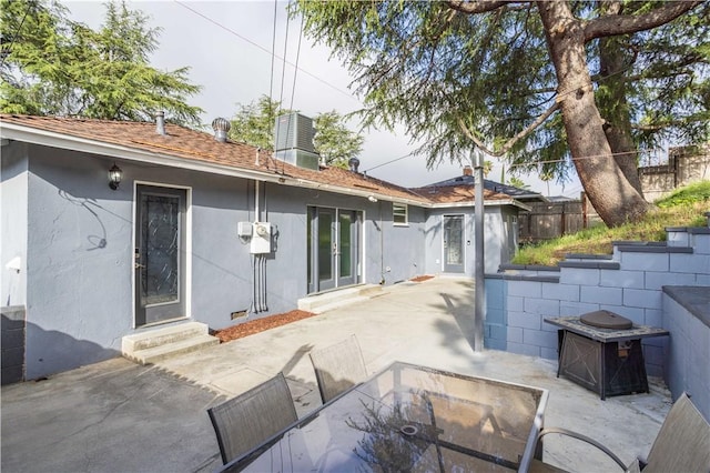 rear view of house featuring entry steps, stucco siding, a patio area, and fence
