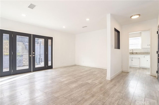 spare room with light wood-style flooring, french doors, baseboards, a sink, and recessed lighting