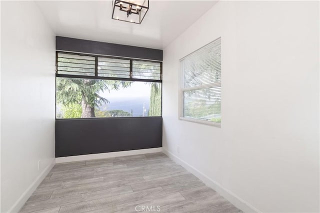 unfurnished room with a chandelier, baseboards, and wood finished floors