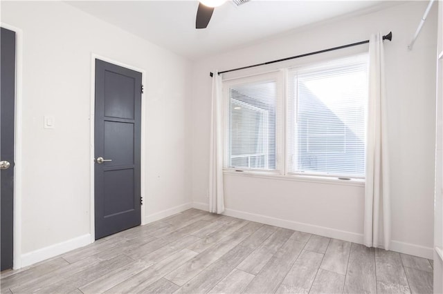 unfurnished room with a ceiling fan, light wood finished floors, baseboards, and plenty of natural light