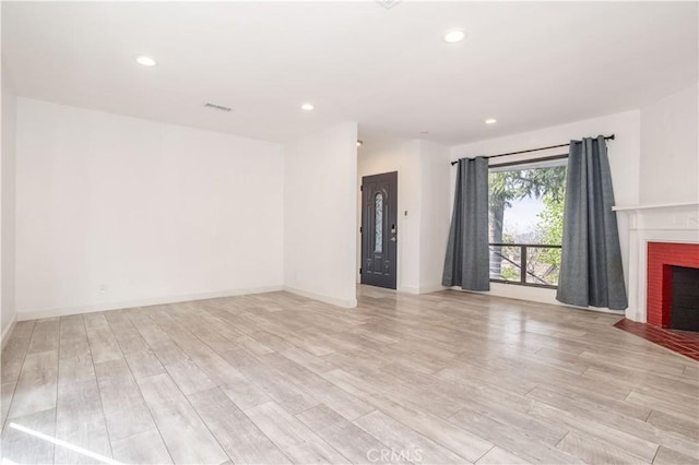 unfurnished living room featuring light wood-type flooring, a fireplace, recessed lighting, and baseboards
