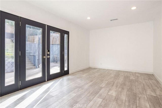 empty room with french doors, light wood-type flooring, recessed lighting, and baseboards