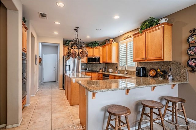 kitchen with stainless steel appliances, a sink, a peninsula, backsplash, and a center island