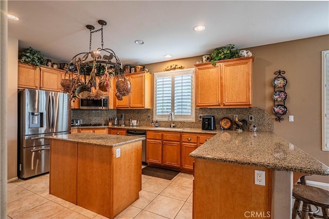 kitchen with appliances with stainless steel finishes, a peninsula, a chandelier, backsplash, and a sink