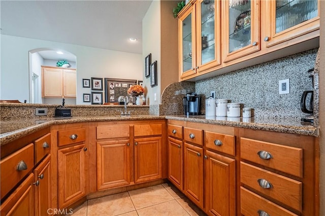 kitchen featuring stone countertops, brown cabinetry, tasteful backsplash, light tile patterned floors, and recessed lighting