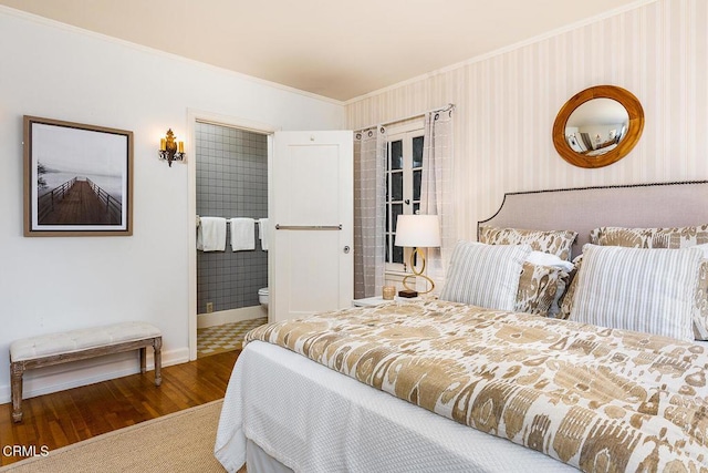 bedroom featuring baseboards, wood finished floors, crown molding, ensuite bathroom, and wallpapered walls