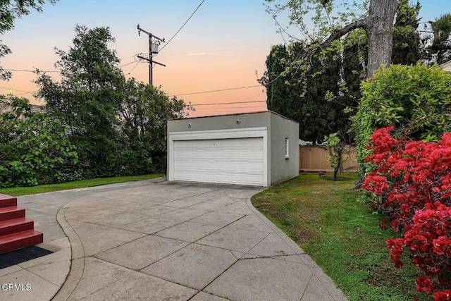garage at dusk featuring fence and a garage