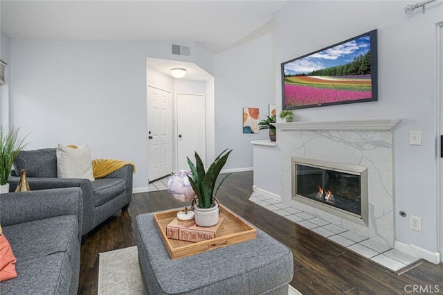 living area with wood finished floors, lofted ceiling, baseboards, and a fireplace