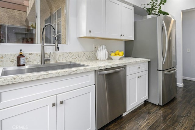 kitchen with appliances with stainless steel finishes, a sink, dark wood finished floors, and white cabinets
