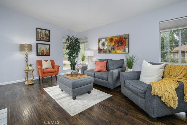 living room with hardwood / wood-style flooring, healthy amount of natural light, vaulted ceiling, and baseboards