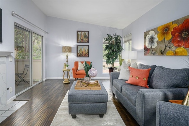 living room featuring wood finished floors, baseboards, and vaulted ceiling