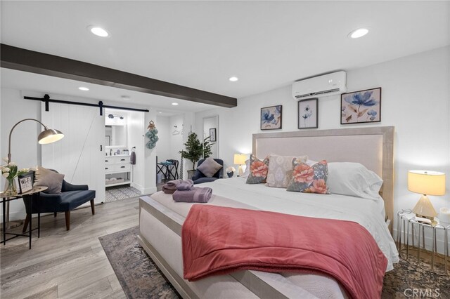 bedroom with a wall mounted AC, a barn door, wood finished floors, beamed ceiling, and recessed lighting