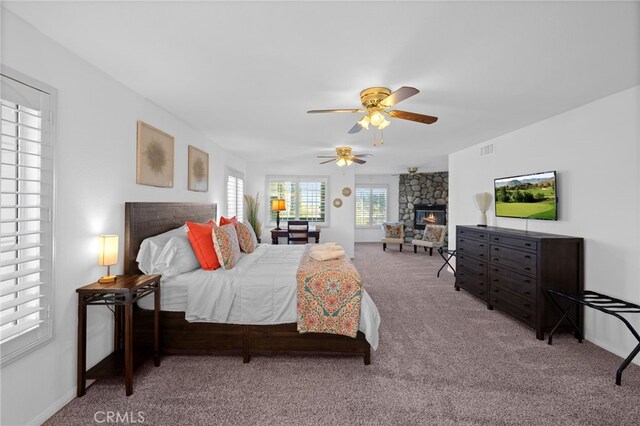 carpeted bedroom featuring a fireplace, a ceiling fan, and baseboards