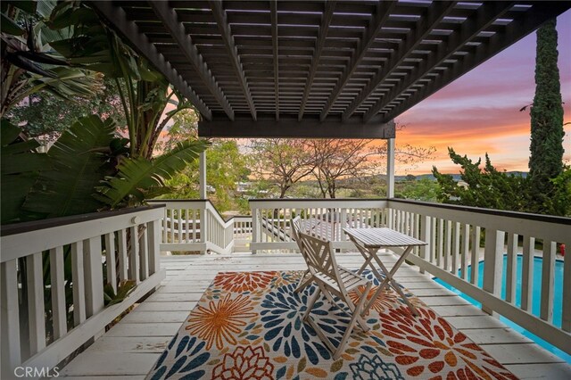 deck at dusk featuring an outdoor pool and a pergola