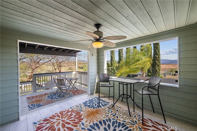 wooden terrace with ceiling fan, outdoor dining area, and a mountain view