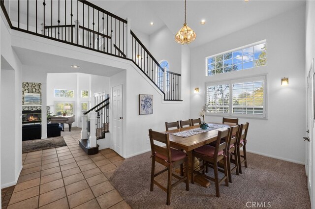 dining area featuring stairway, a towering ceiling, plenty of natural light, a chandelier, and baseboards
