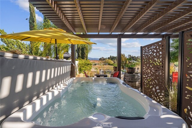view of patio / terrace with a hot tub and fence