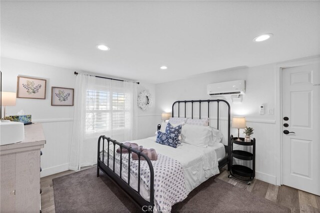 bedroom featuring a wall mounted air conditioner, wainscoting, wood finished floors, and recessed lighting