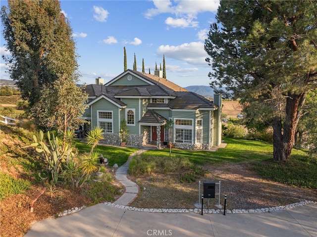 bungalow-style house featuring a chimney, a front lawn, and stone siding