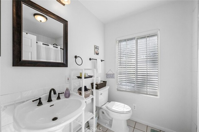 bathroom featuring a sink, toilet, tile patterned flooring, and a shower with curtain