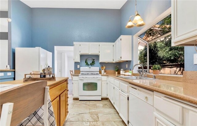 kitchen featuring white appliances, a sink, light countertops, a high ceiling, and white cabinets