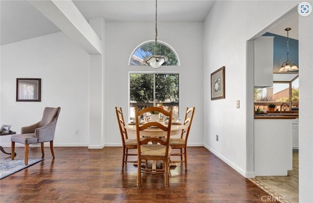 dining area featuring dark wood-type flooring, a chandelier, and baseboards