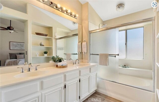bathroom with ensuite bath, ceiling fan, double vanity, wood finished floors, and vaulted ceiling