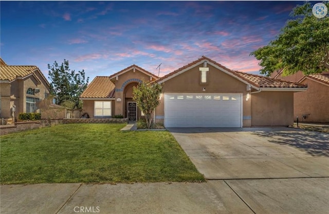 view of front of home with stucco siding, an attached garage, a tile roof, a lawn, and driveway