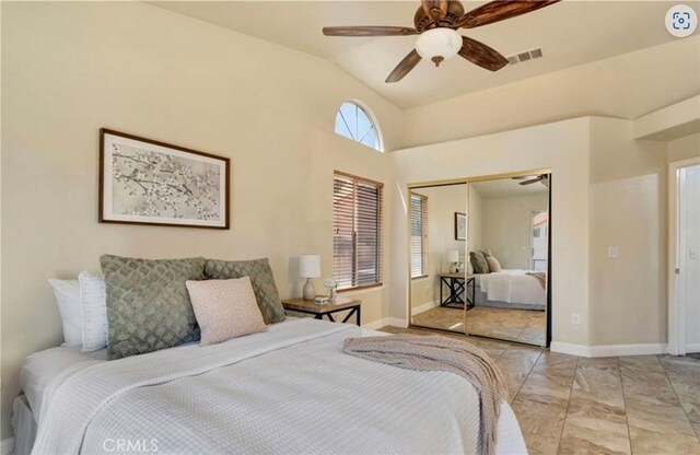 bedroom with a closet, vaulted ceiling, a ceiling fan, light marble finish flooring, and baseboards