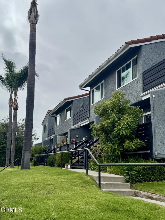view of front of home featuring stucco siding, a front yard, and a tiled roof