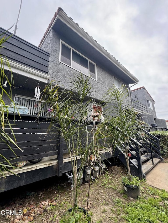 view of side of home with stucco siding and a tiled roof