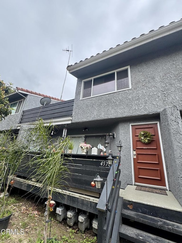 rear view of house featuring stucco siding