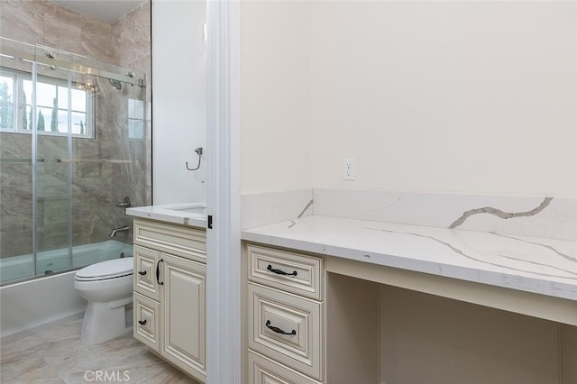 bathroom featuring toilet, vanity, and shower / bath combination with glass door