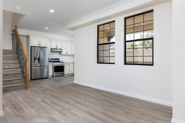 kitchen featuring stainless steel appliances, crown molding, under cabinet range hood, baseboards, and light wood-style flooring