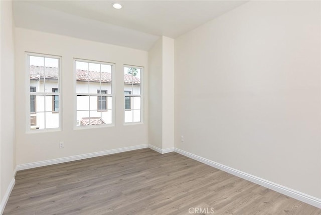 empty room featuring baseboards, light wood-style flooring, recessed lighting, and lofted ceiling