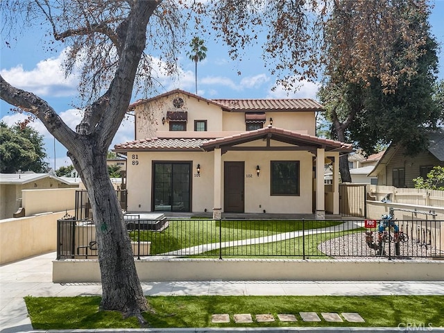 mediterranean / spanish home featuring stucco siding, a tile roof, and a gate