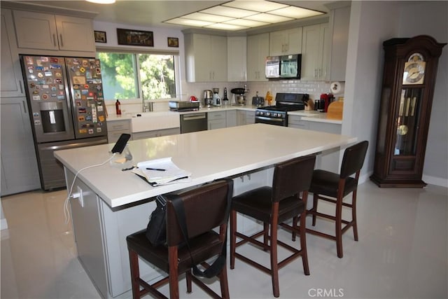 220 S Guadalupe Ave Unit 5, Redondo Beach, CA 90277 - kitchen featuring appliances with stainless steel finishes, a sink, backsplash, and a breakfast bar